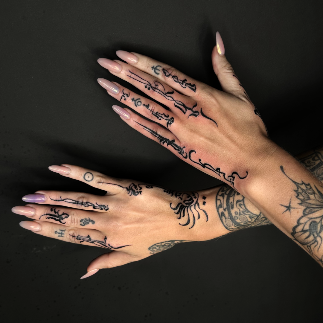 Abstract and asemic calligraphy tattoo on the fingers and wrist