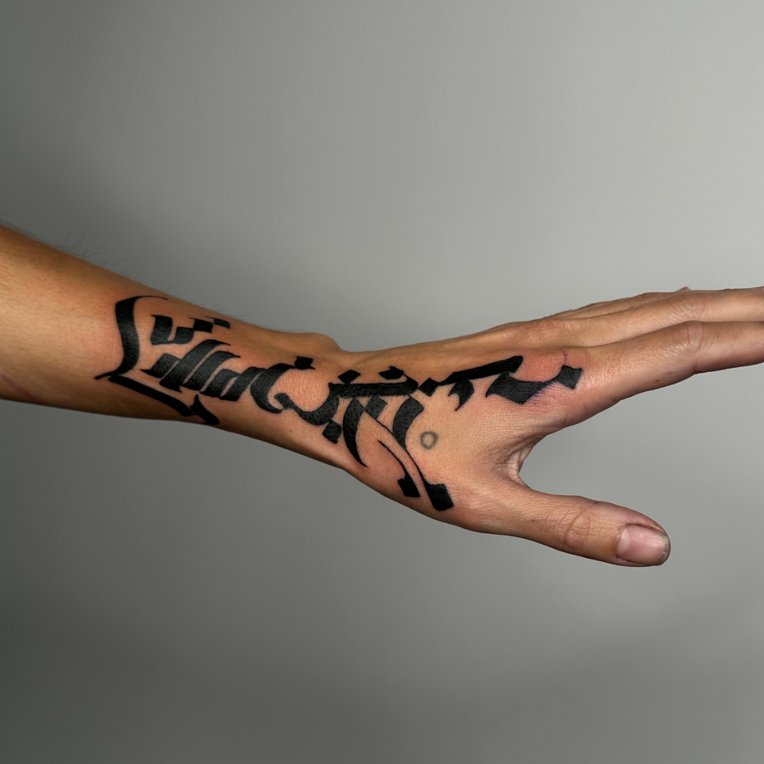 Abstract and asemic calligraphy tattoo on the wrist and hand