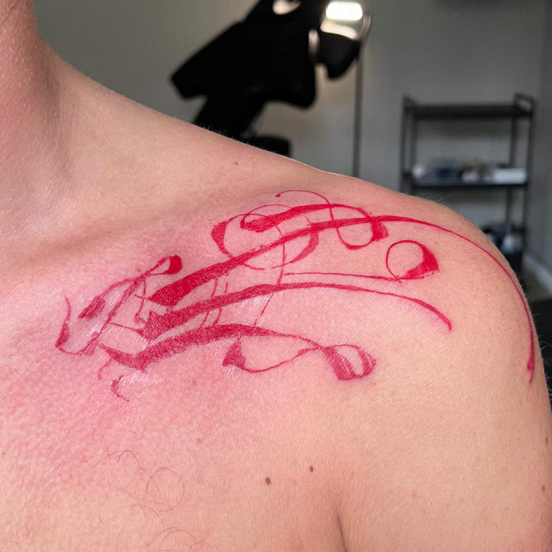 Abstract and asemic calligraphy tattoo on the shoulder and collarbones