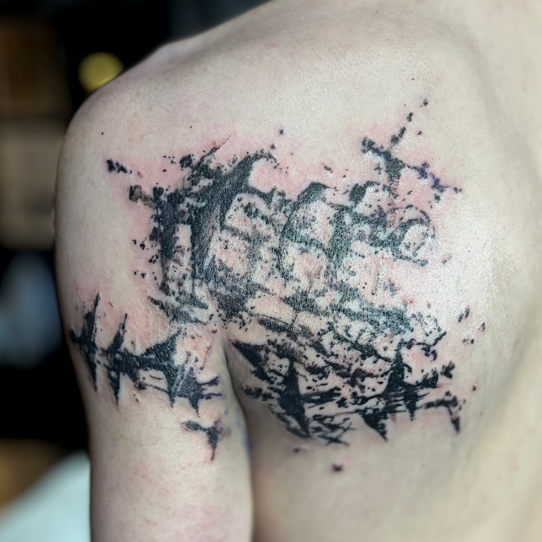 Abstract ink splatter tattoo on the shoulder blade and arm