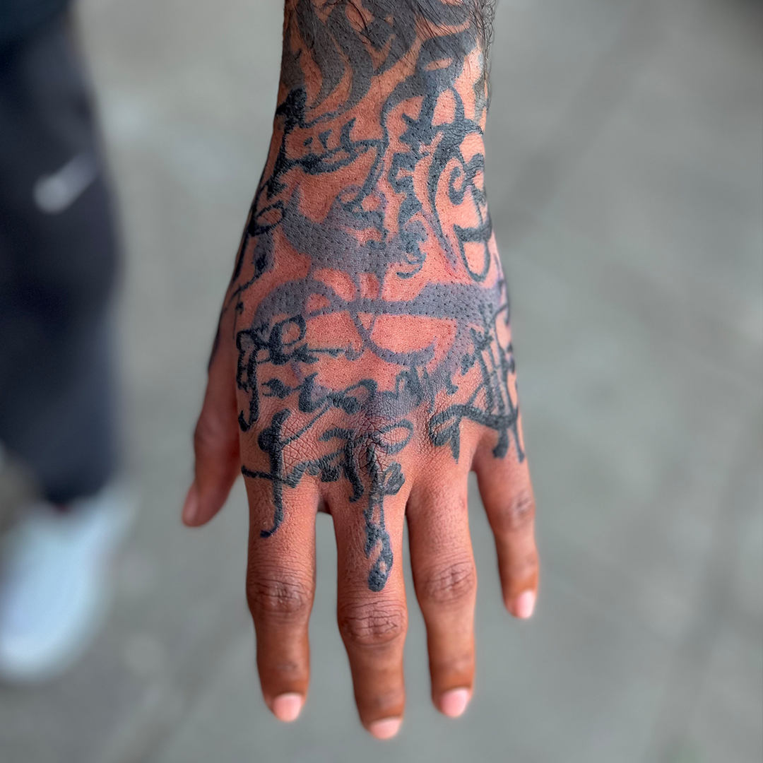 Abstract and asemic calligraphy tattoo on the back of the hand