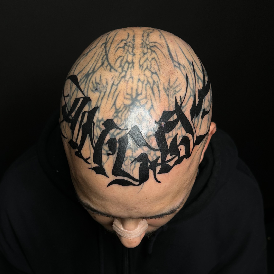 Bold black calligraphy tattoo on the forehead