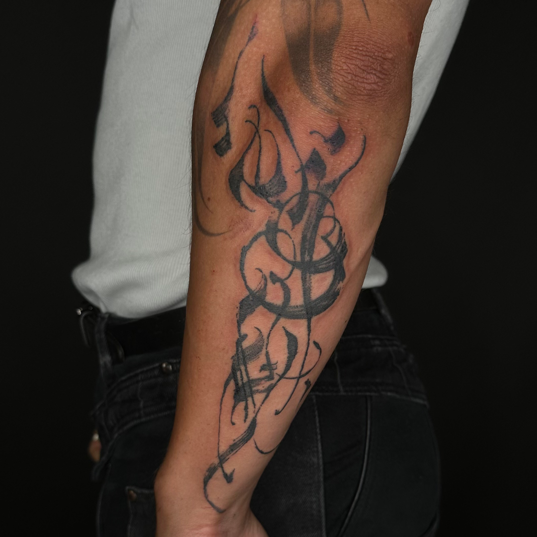 Abstract and asemic calligraphy tattoo on the forearm