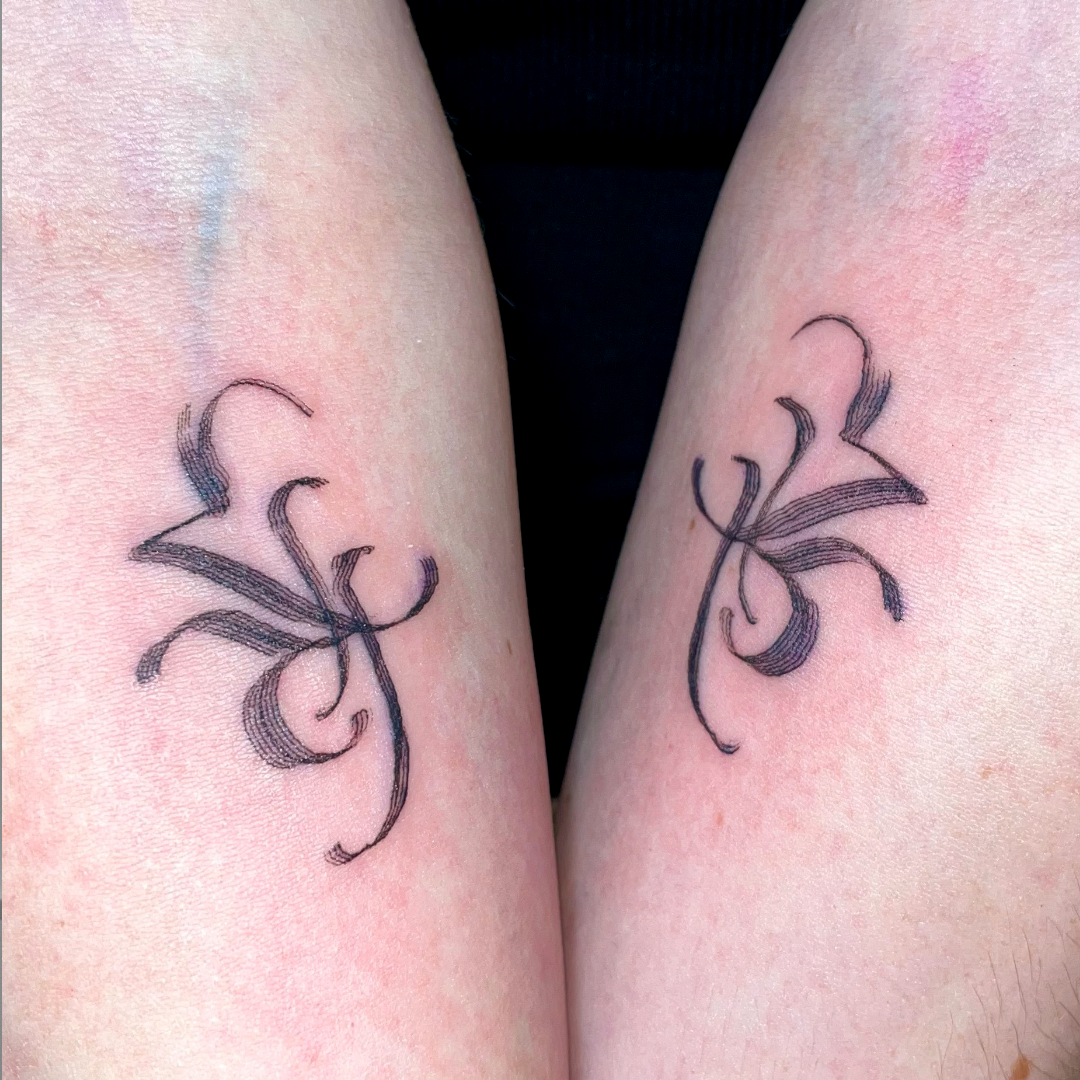 Abstract and asemic symmetrical calligraphy tattoo on the forearm