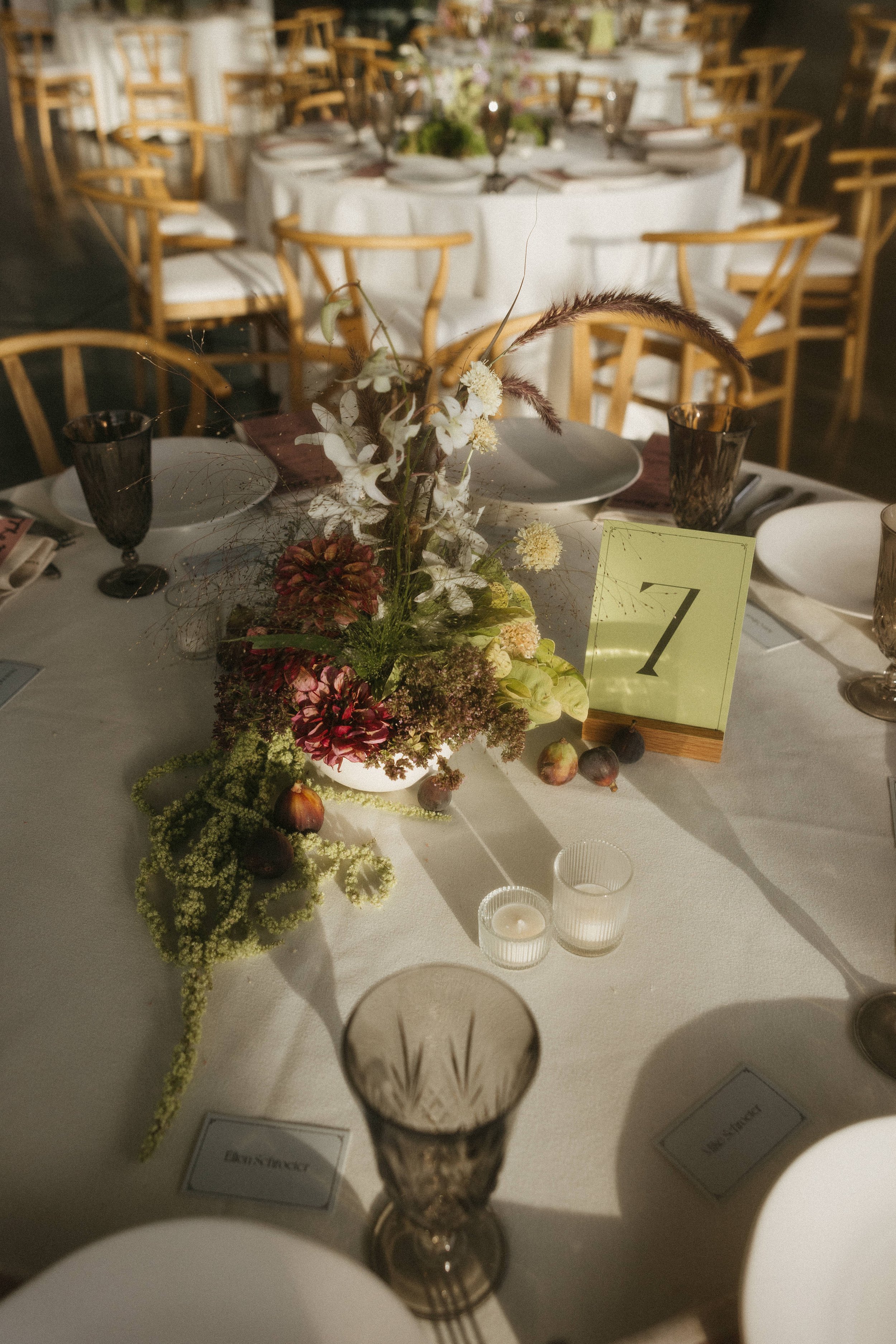 A banquet table decorated with a floral centerpiece, candles, and tableware, set for an event in a well-lit room.