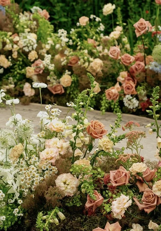 A variety of colorful flowers including roses, daisies, and other blooms arranged in a garden.