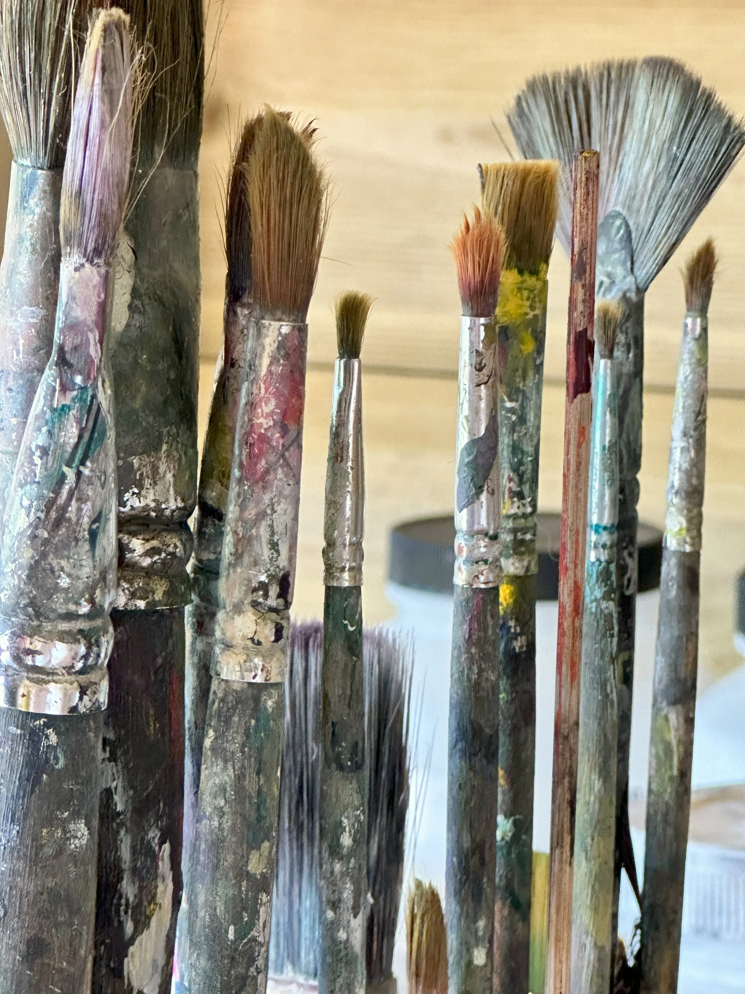 Close up images of used paintbrushes in the artist's studio