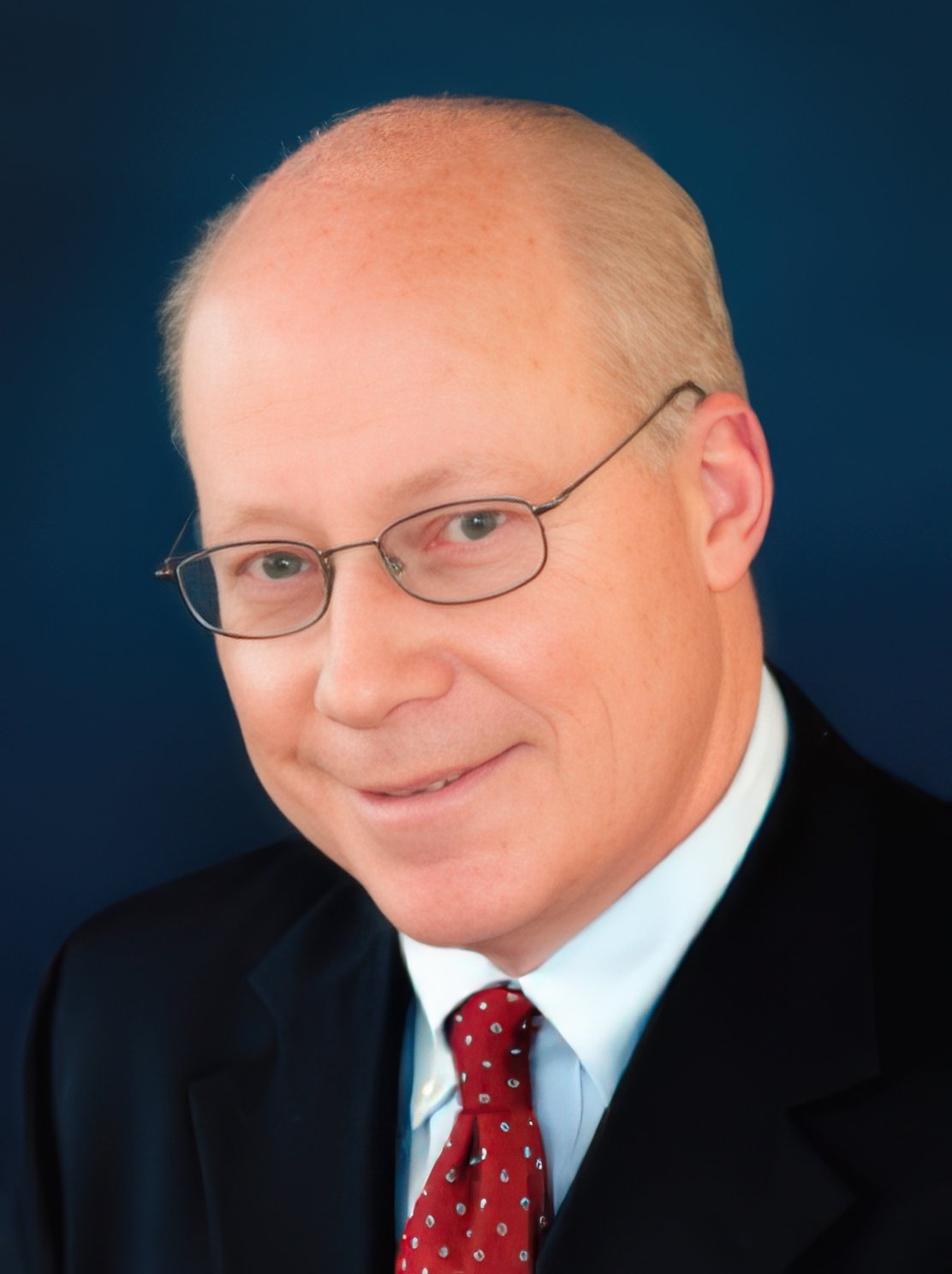 Smiling person in a gray plaid suit against a teal background.