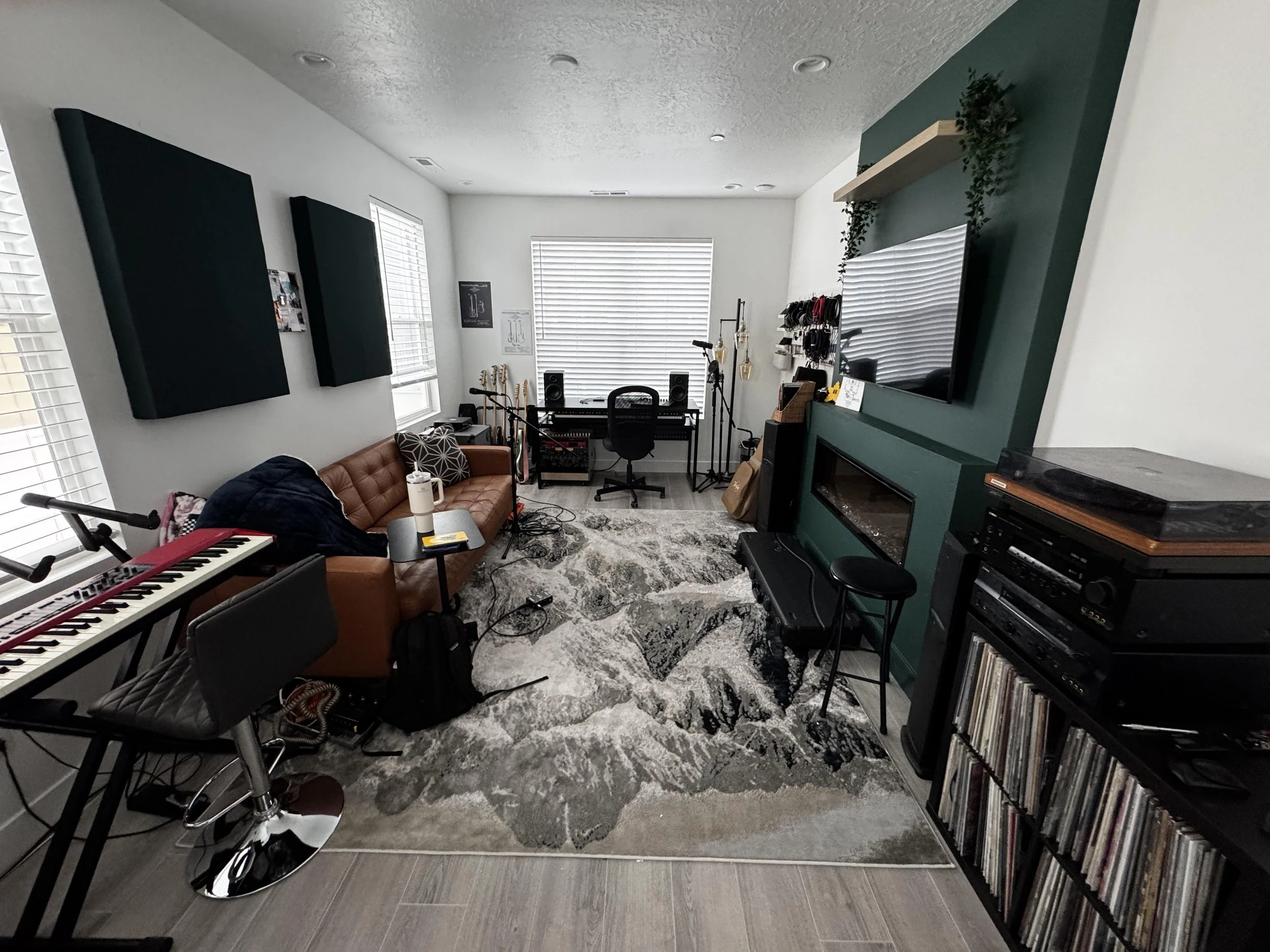 Modern music recording studio at Willow Street Studios featuring a Nord keyboard, leather sofa, acoustic wall panels, and a vinyl record collection in a bright, creative workspace.