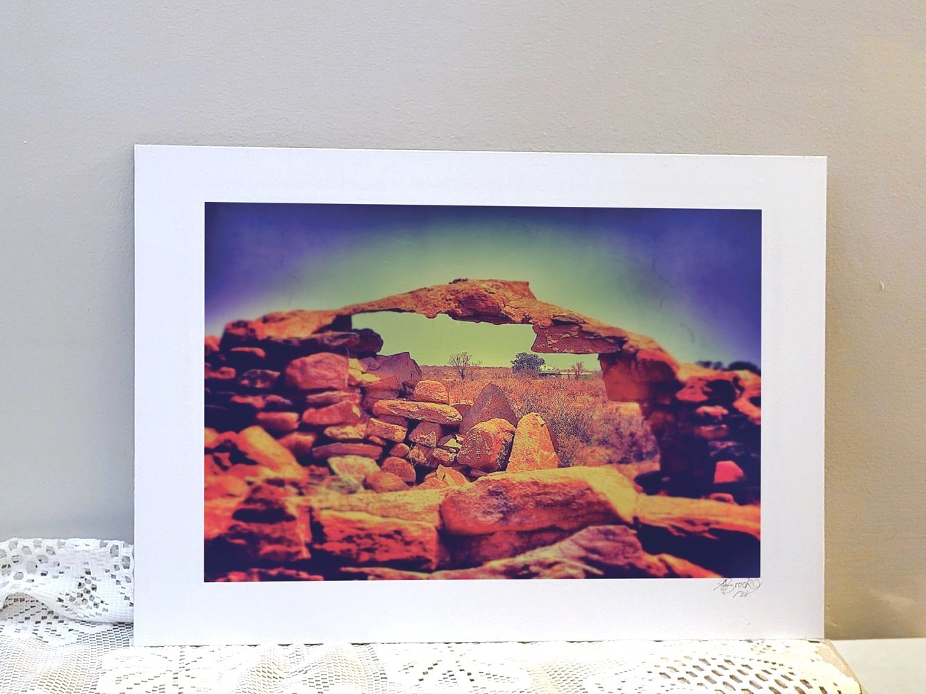 Metal backed photograph of rock arch formation with vegetation background in outback Australia