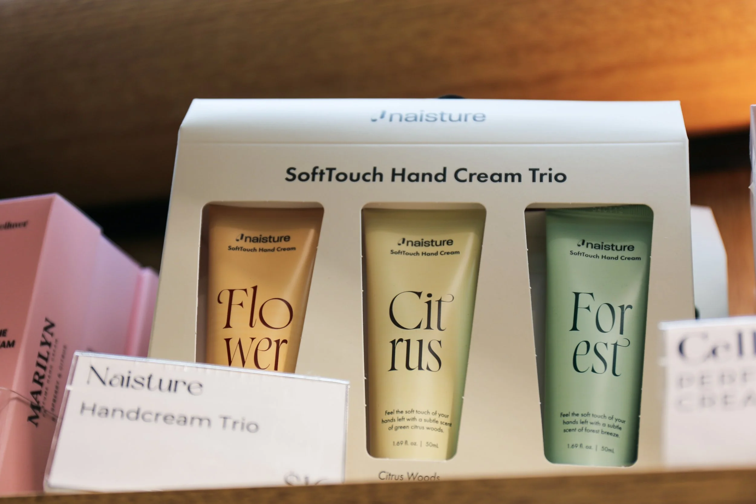 A set of three Naisture SoftTouch Hand Cream tubes labeled 'Flower,' 'Citrus,' and 'Forest' inside a white box display.