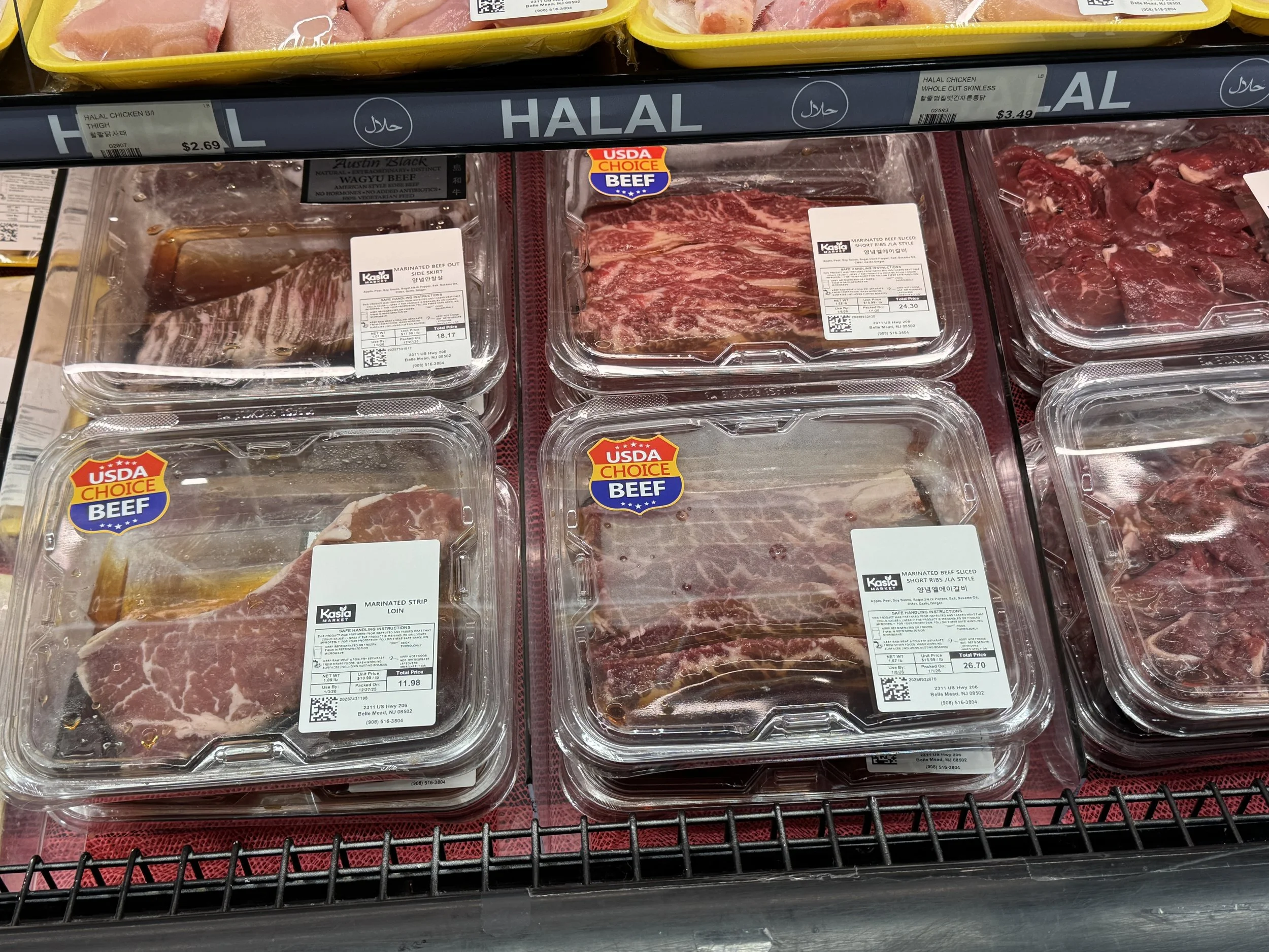 Various packages of beef and chicken meat in a refrigerated meat section of a grocery store, labeled with USDA Choice and halal, including marinated strips, sliced, and short ribs.