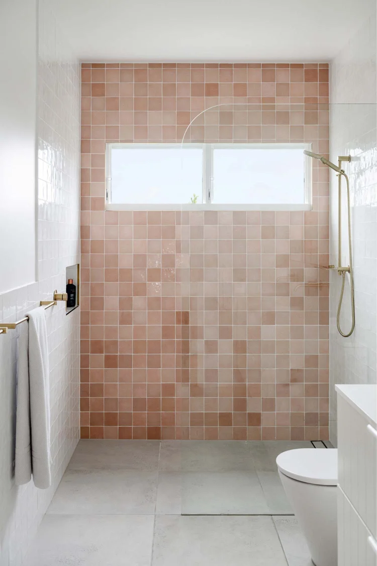 Bathroom with soft pink feature tiles and brushed gold tapware at the Warilla Beach House