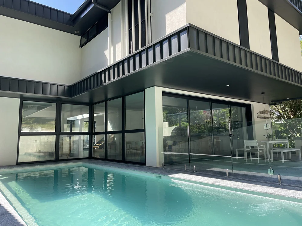 Railway Austinmer: new two-storey home with full-height glazing opening to an inground pool, built by CKS Projects