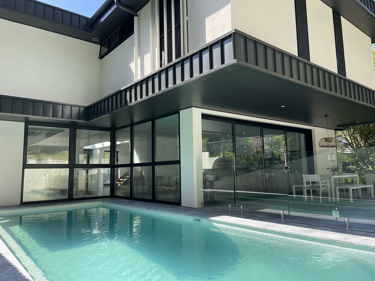 Railway Austinmer: new two-storey home with full-height glazing opening to an inground pool, built by CKS Projects