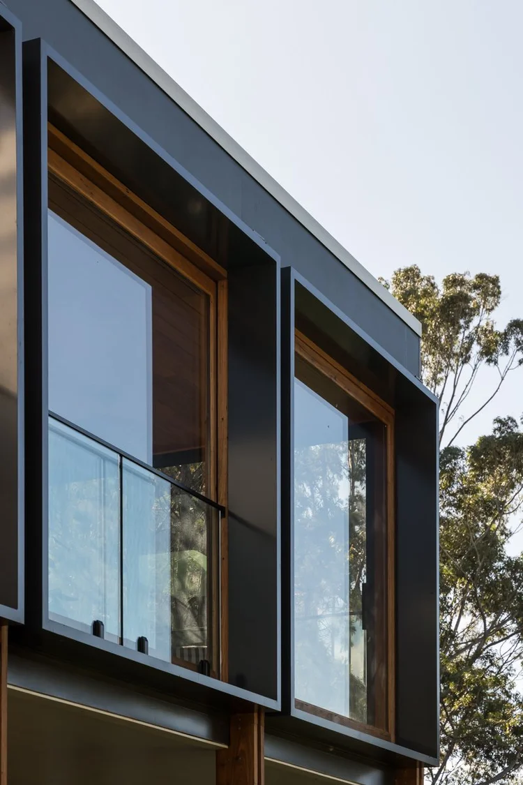 Close-up of dark window frames set into timber reveals and a glass balustrade, Coledale renovation detail