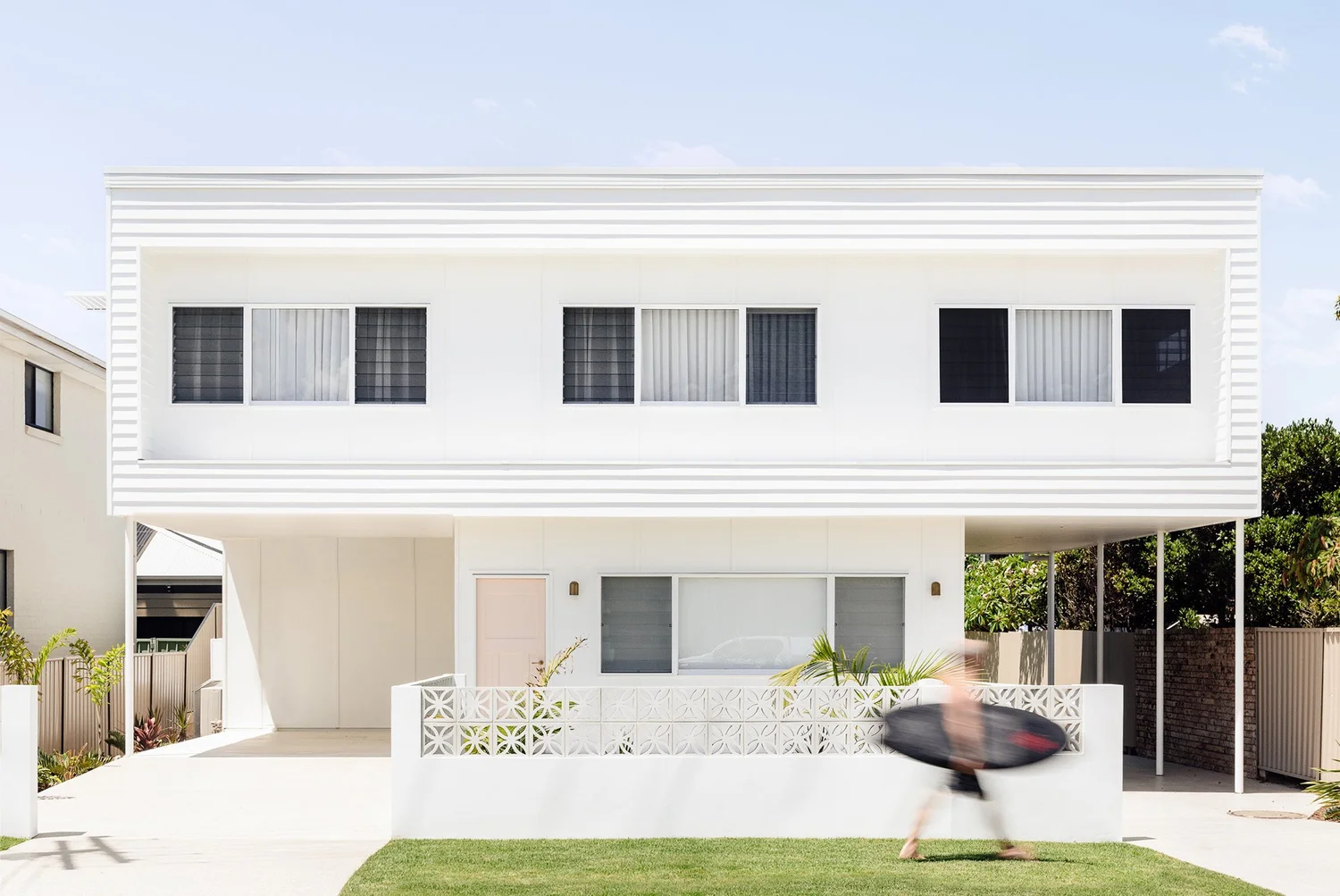 Warilla Beach House: white two-storey beach house with a breeze-block front fence, renovated with a first-floor addition by CKS Projects