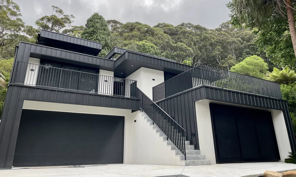 Railway Austinmer, a dark-clad two-level home set against escarpment bushland, built by CKS Projects