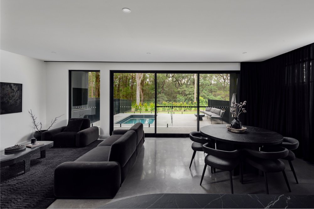 Monochrome living and dining room with polished concrete floor and glazing to the pool, Huskisson Duplex by CKS Projects