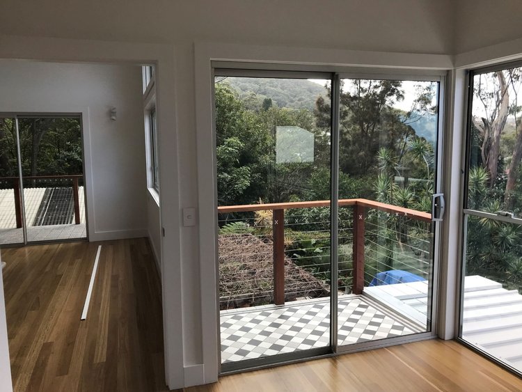 Upper-level room in the Wombarra addition with timber floors and sliding doors to a balcony