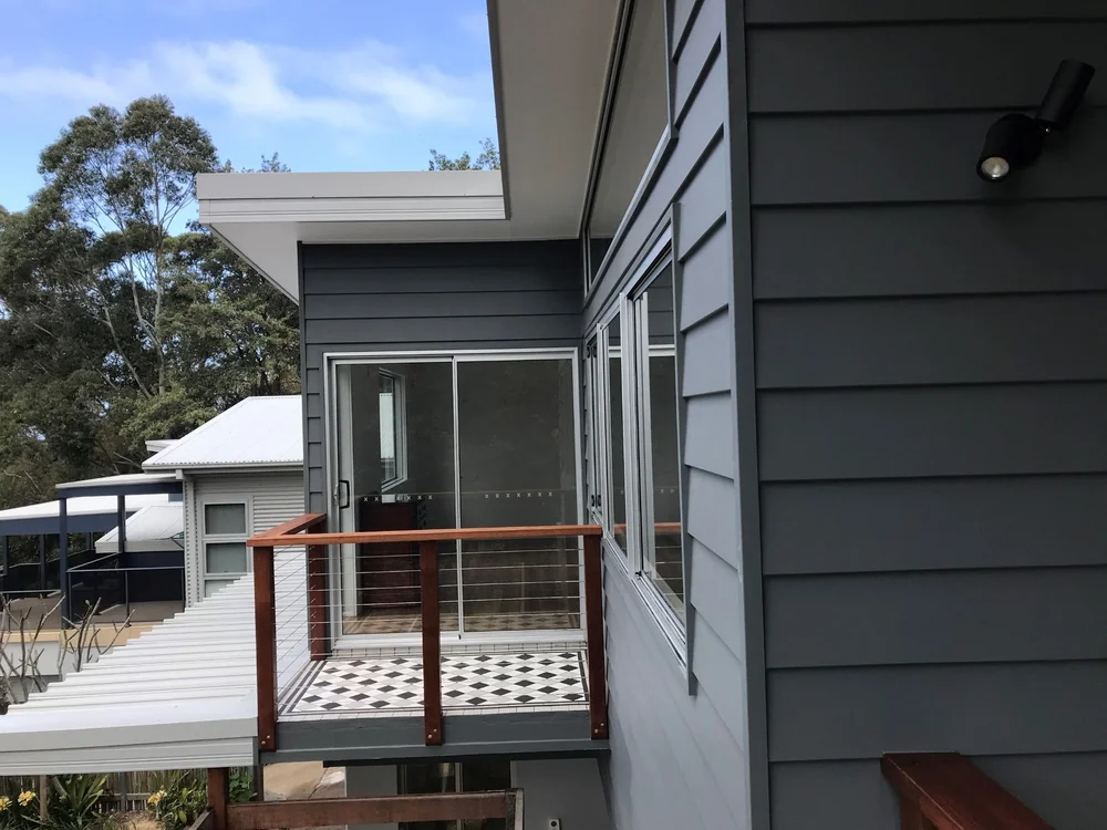 Clad exterior of the Wombarra second-storey addition with a timber-railed balcony, by CKS Projects