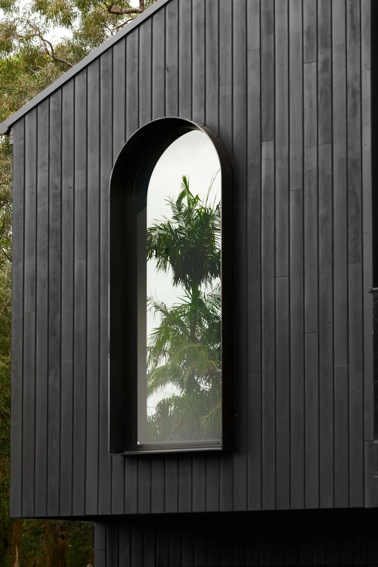 Arched window set into charred Shou Sugi Ban timber cladding on the Huskisson duplex built by CKS Projects