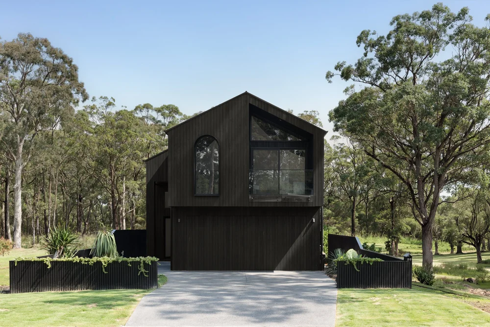 Huskisson duplex with dark charred-timber cladding in coastal bushland, built by CKS Projects