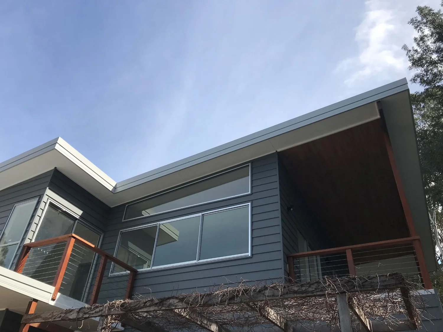 Second-storey addition with weatherboard cladding and skillion roof on a steep coastal block in Wombarra, built by CKS Projects