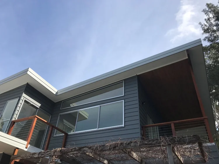 Second-storey addition with weatherboard cladding and skillion roof above the original Wombarra cottage