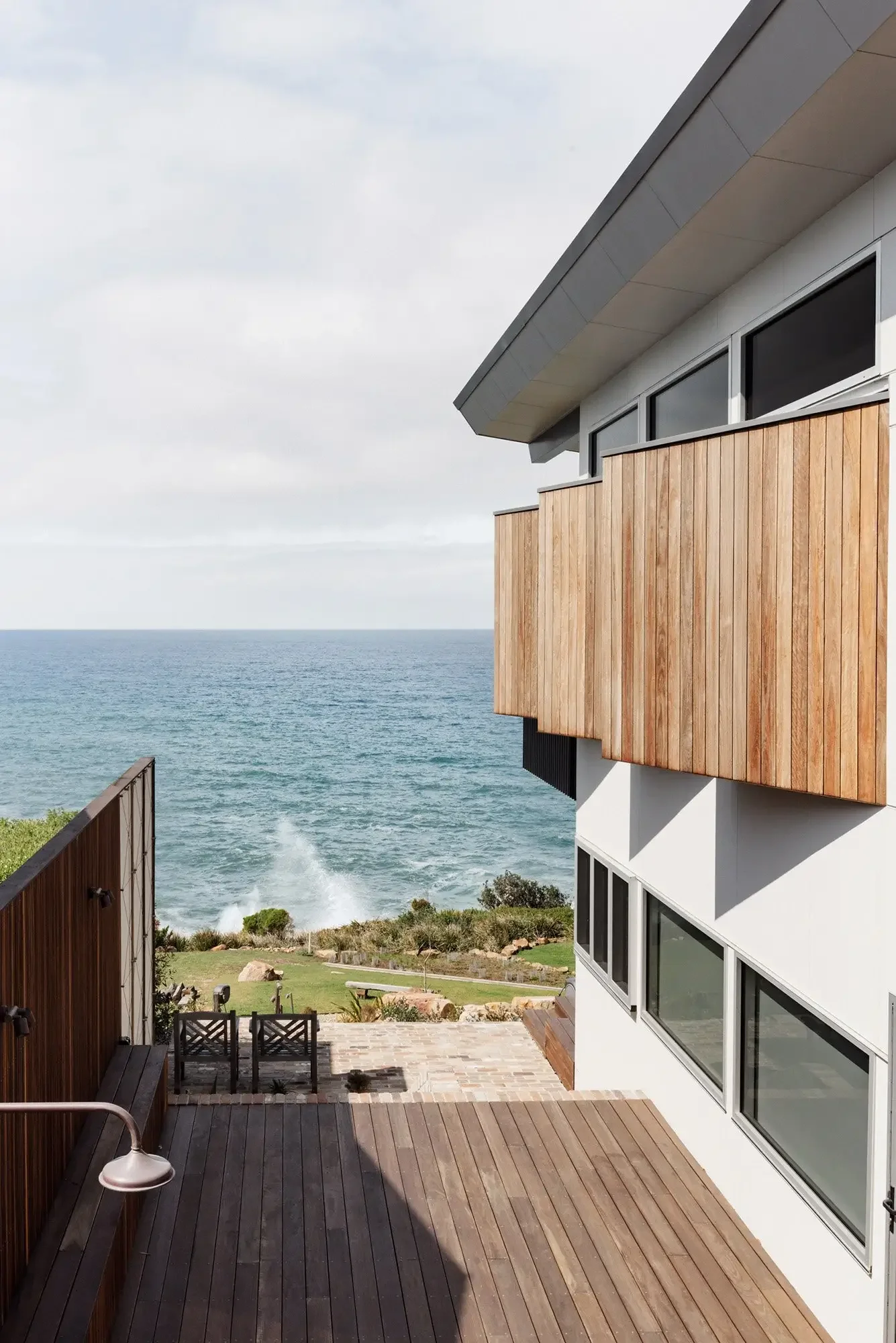Timber-clad upper level and deck looking over the ocean at Wombarra Clifftops by CKS Projects