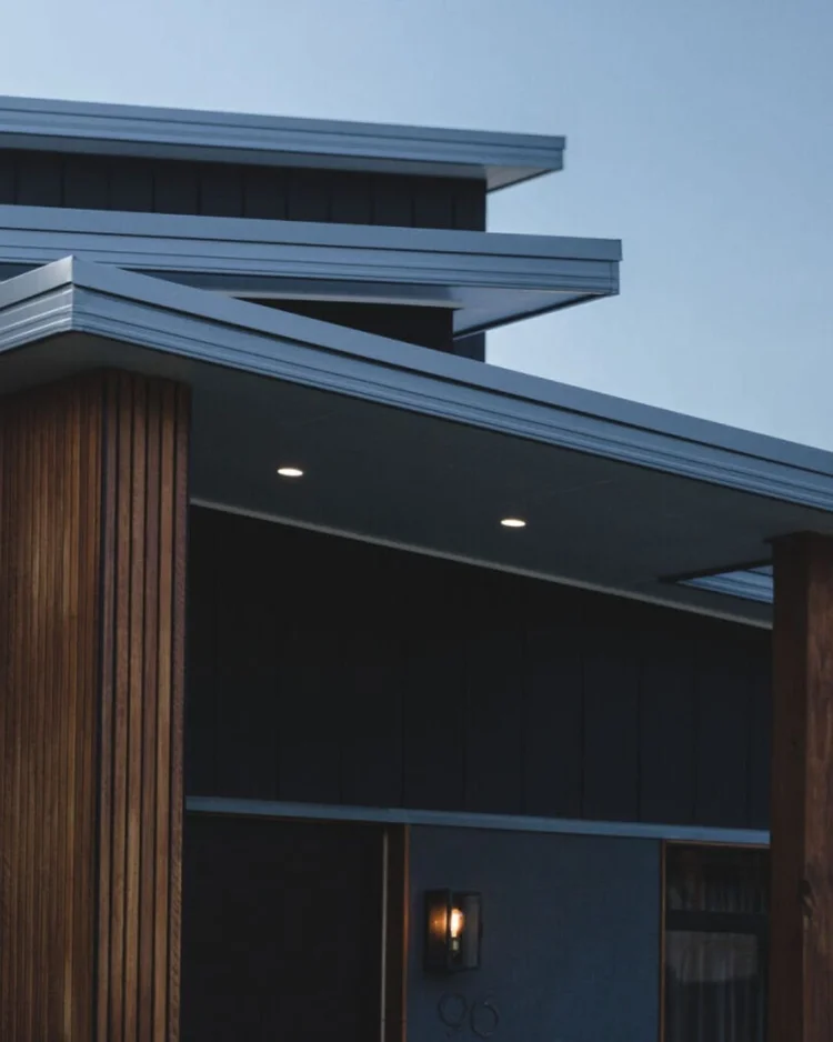 Deep eaves and vertical timber cladding shading the facade of a home