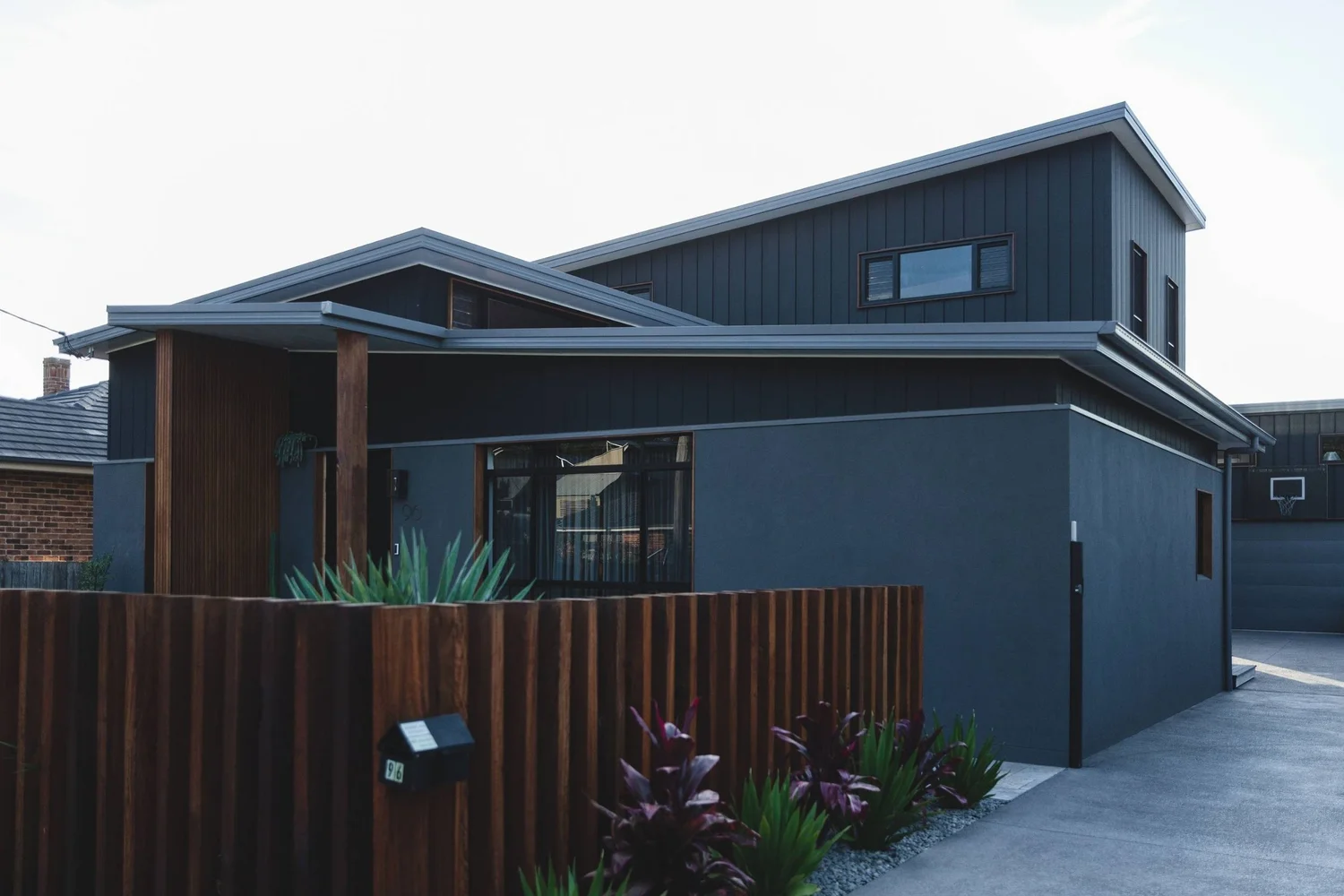 Ocean Windang: a two-storey home in black cladding with timber accents, extended and renovated by CKS Projects