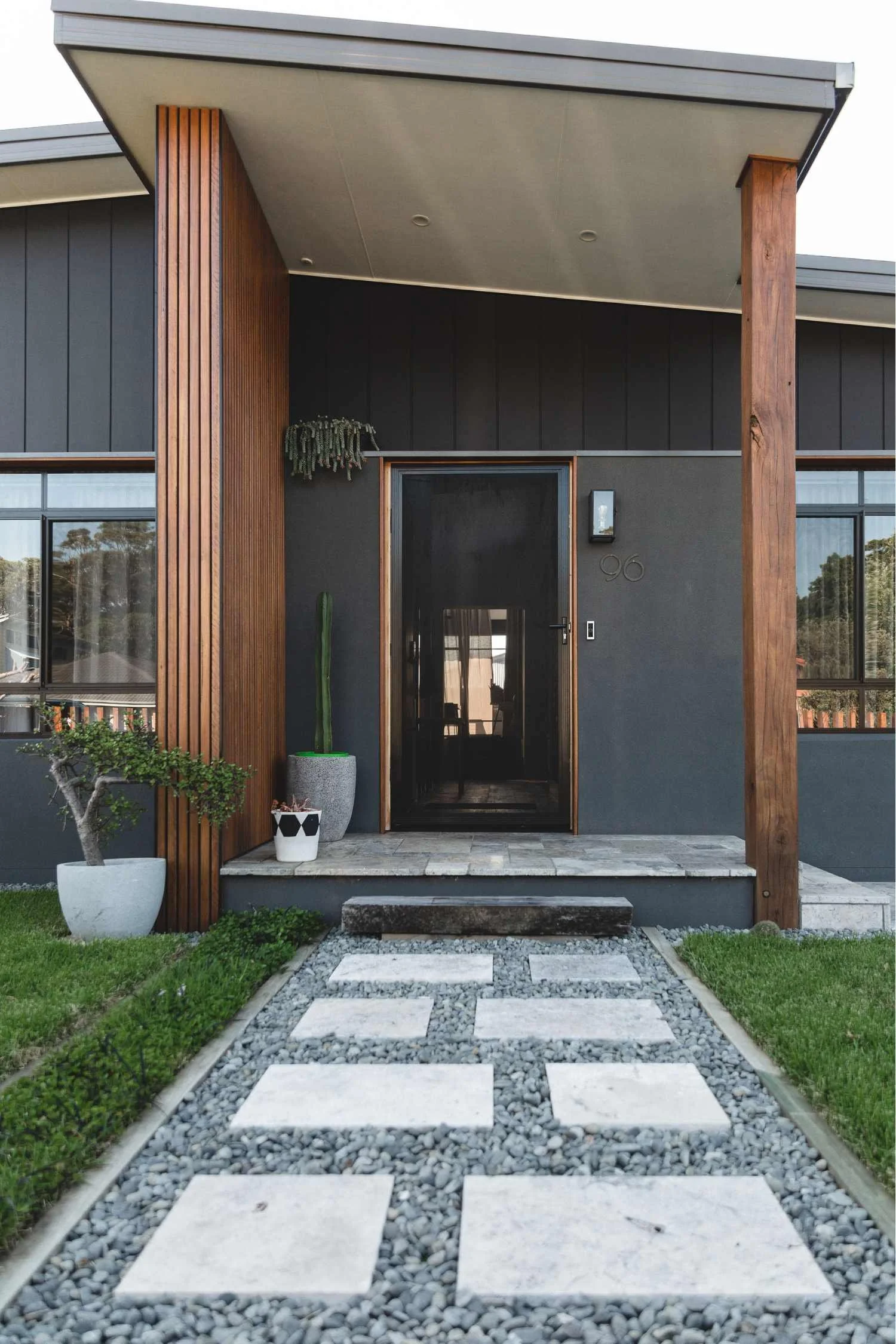 Entry to Ocean Windang: timber-clad portico, dark cladding and a stepping-stone path