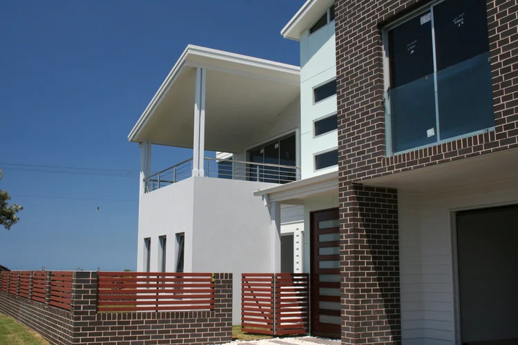 Two-storey attached homes with brick and rendered facades and upper balconies