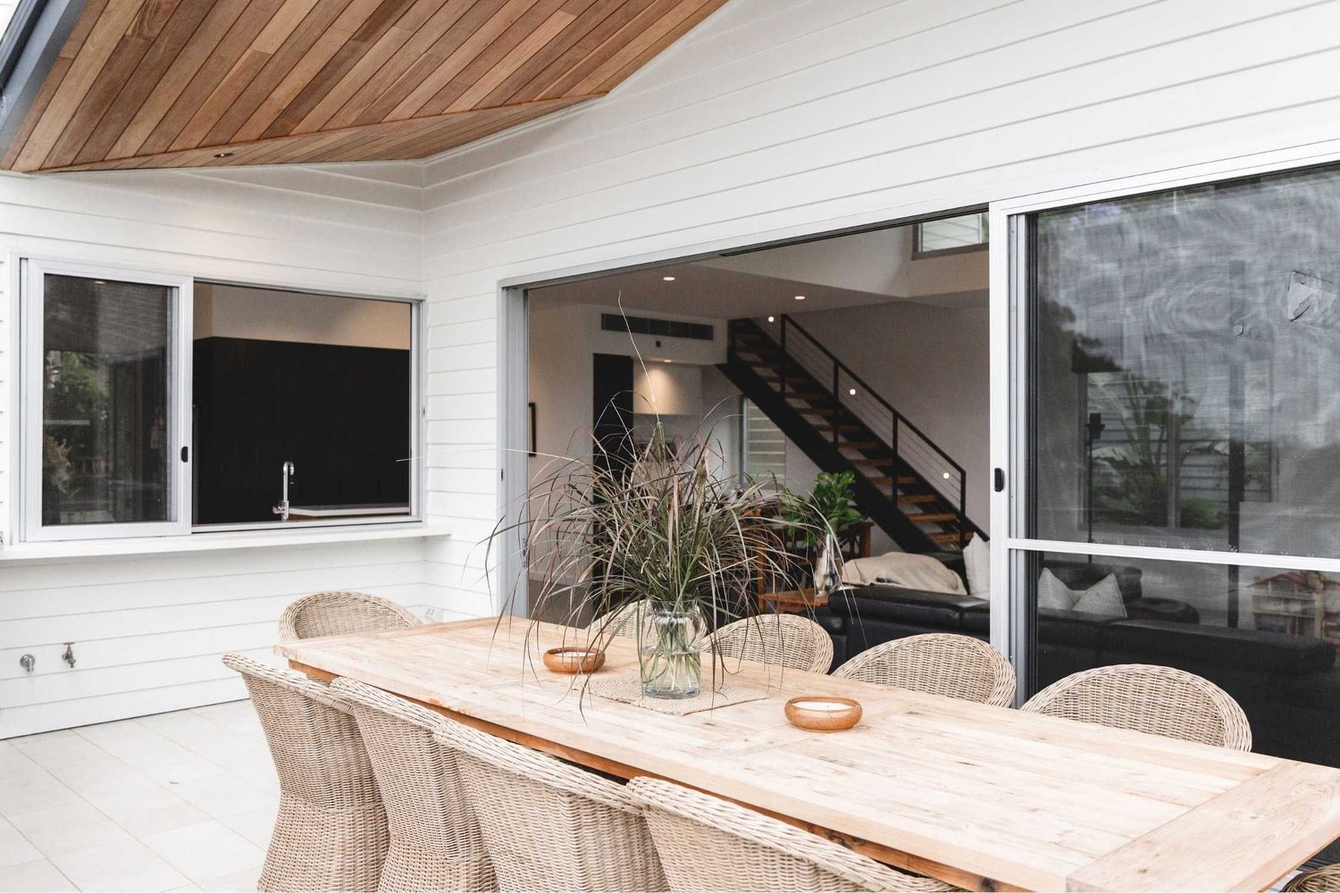 Dining area under a timber-lined ceiling opening to the living room and stair, Sandhurst Bulli by CKS Projects