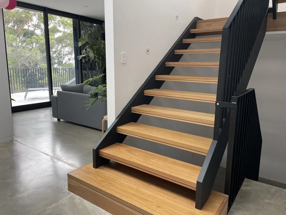 Timber stair treads with black steel stringers over a polished concrete floor, Railway Austinmer by CKS Projects