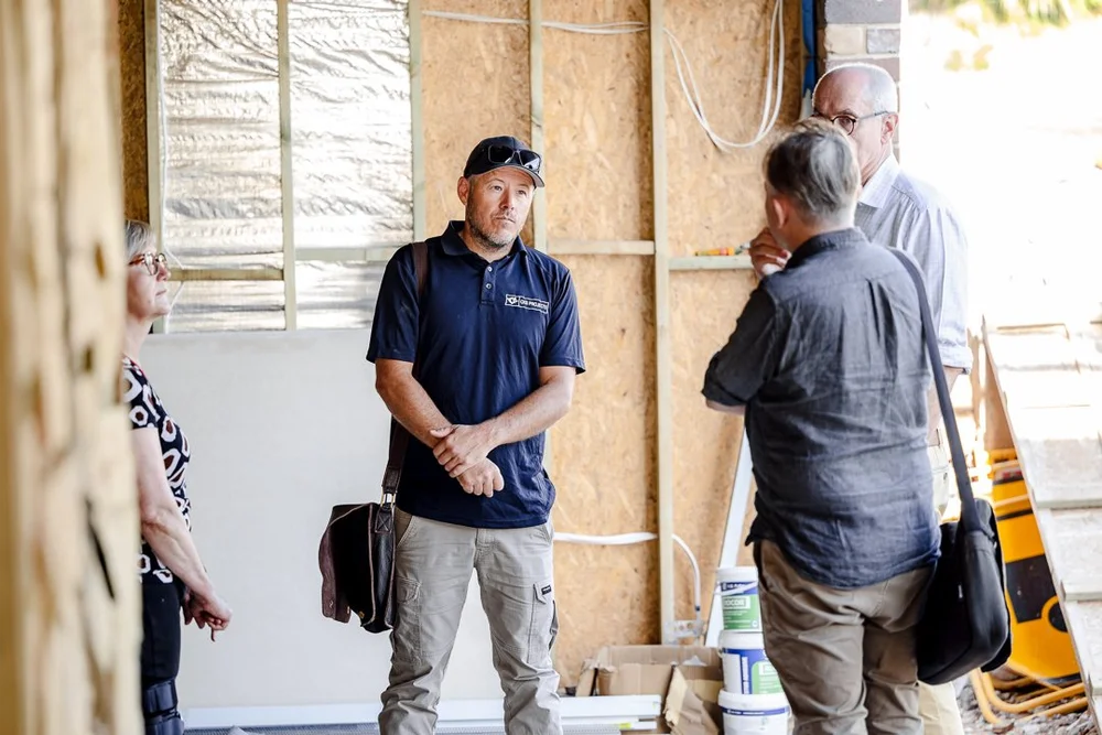 A CKS Projects team member meeting clients inside the timber frame at Wombarra during construction