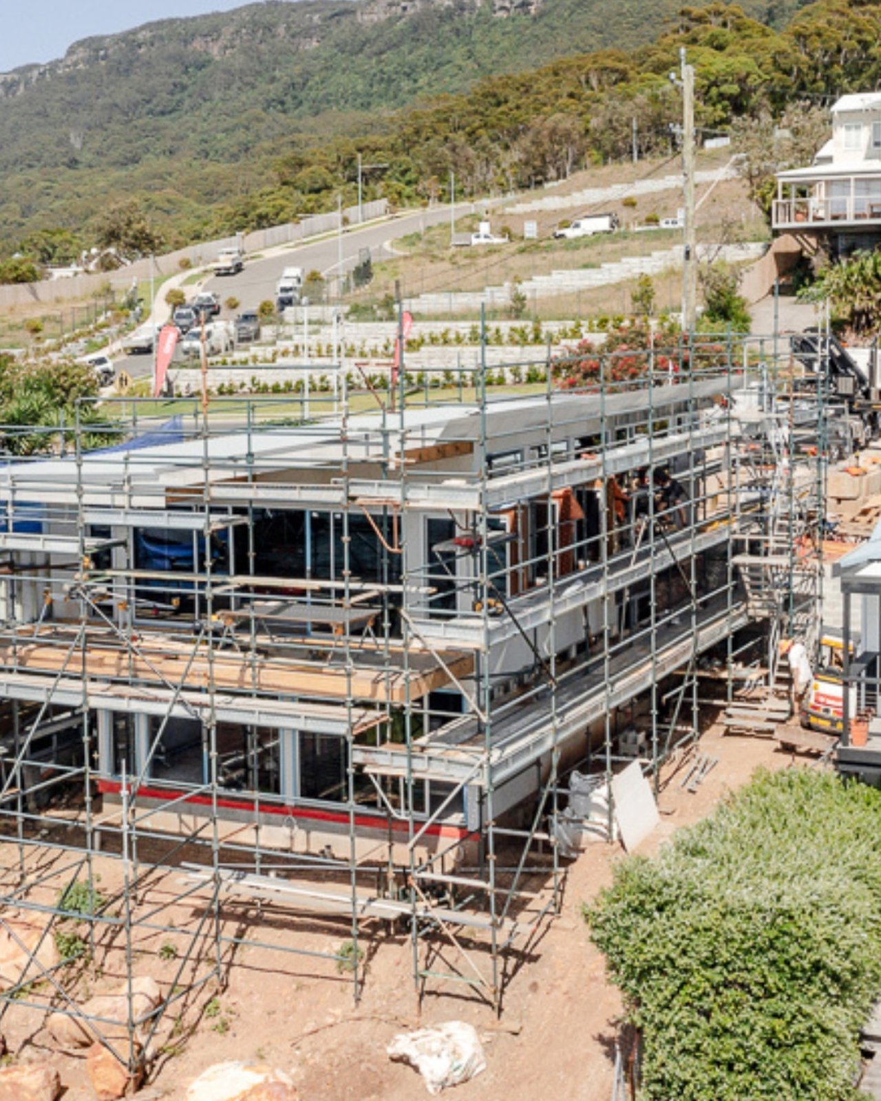 New home under construction in scaffolding on a sloping street below the Illawarra escarpment