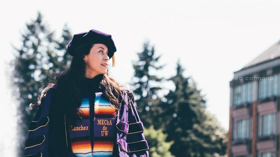 Irene Sanchez standing at the University of Washington in Ph.D. regalia
