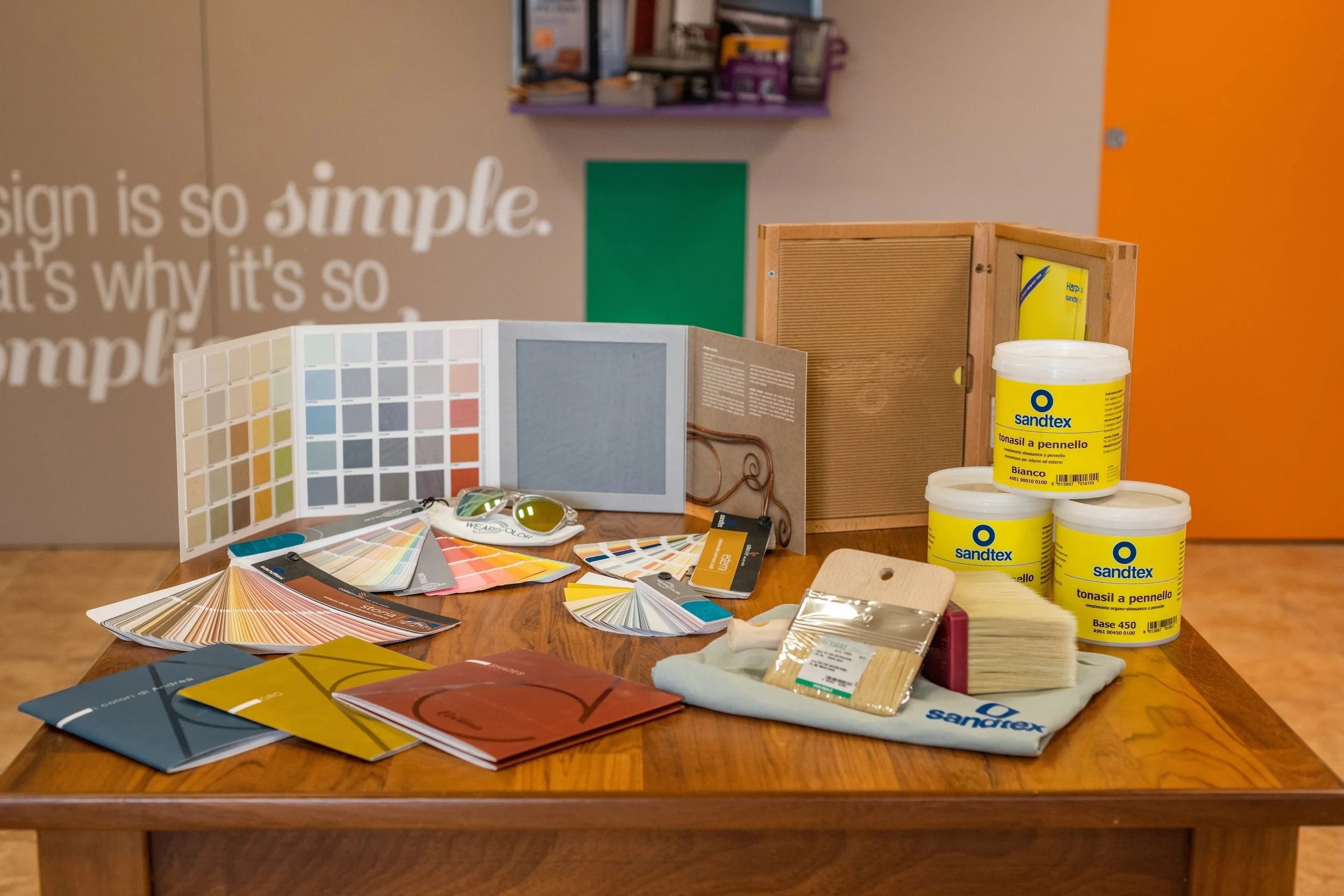 Selezione di materiali di arredamento e vernici, tra cui campioni di colore, tinte, tessuti, strumenti di pittura e legno su un tavolo, utilizzati per la decorazione d'interni.