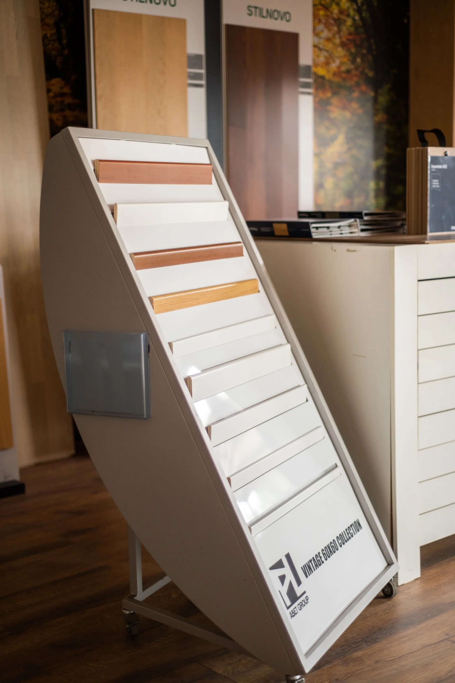 Espositore con vari campioni di laminato e legno, intitolato 'VINTAGE 60/60 COLLECTION', in un negozio di materiali per l'edilizia o arredamento.
