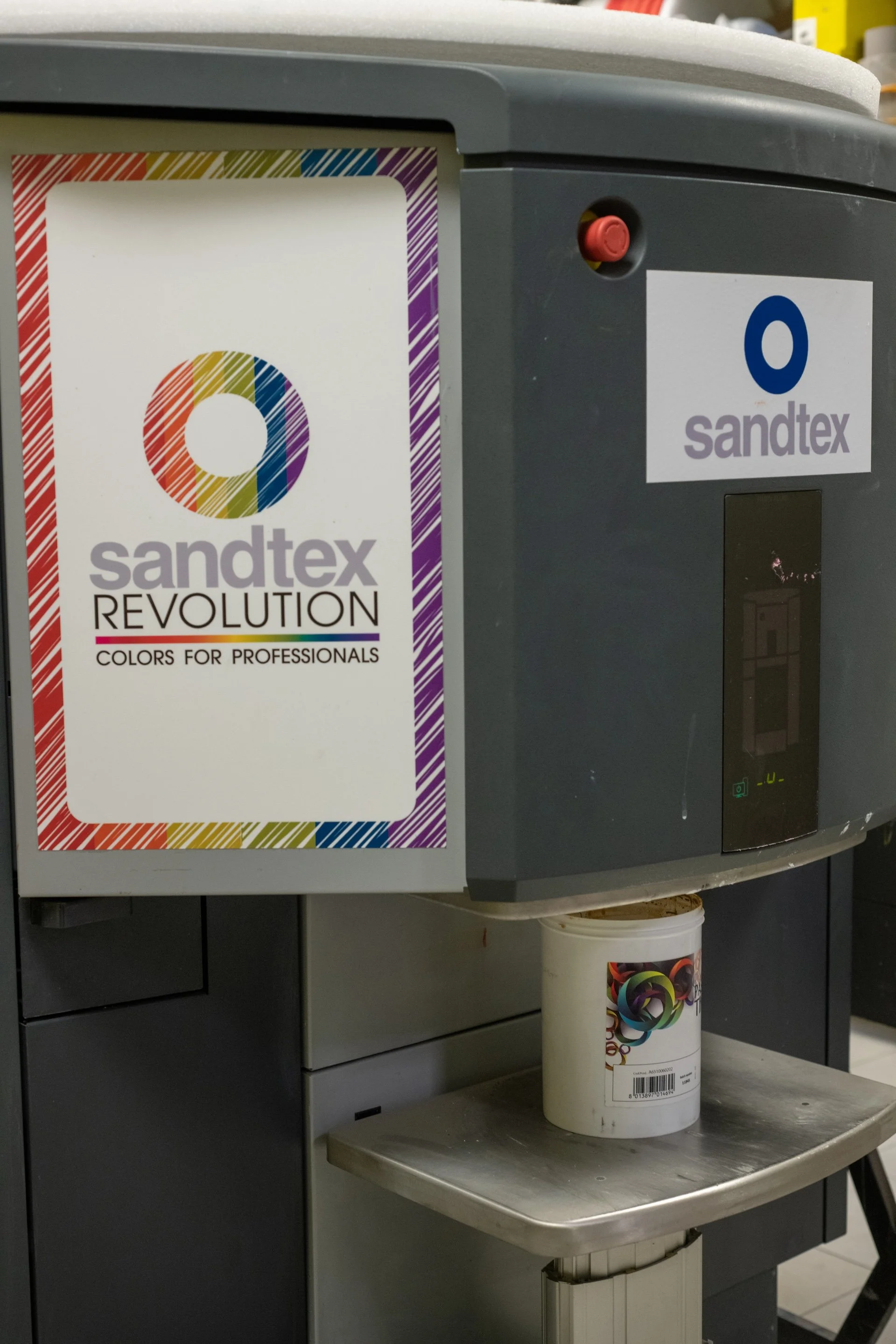 Stampante a getto d'inchiostro Sandtex Revolution con cartuccia di colore bianco e mostrina pubblicitaria colorata.