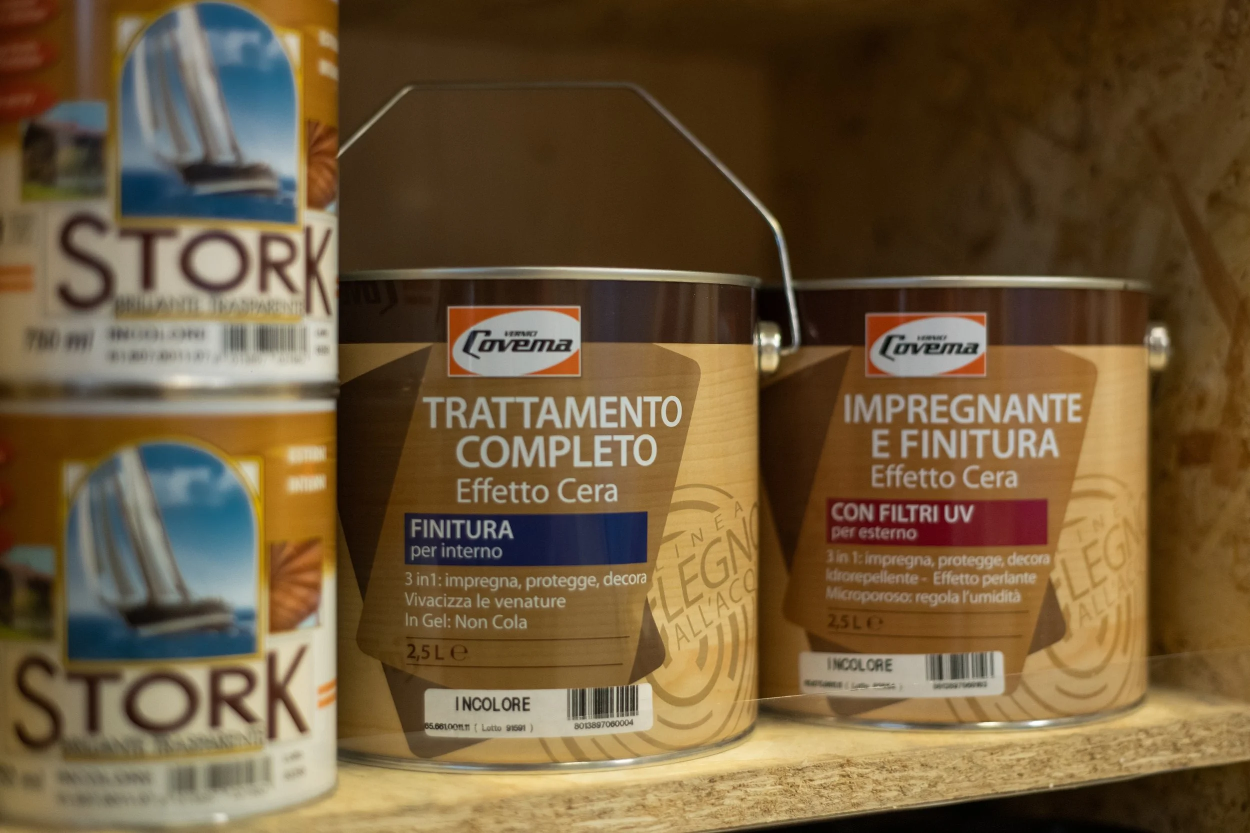 Barattoli di prodotti per la verniciatura e trattamento di superfici, tra cui trattamento completo e impregnante con effetto cera, su scaffale di negozio.