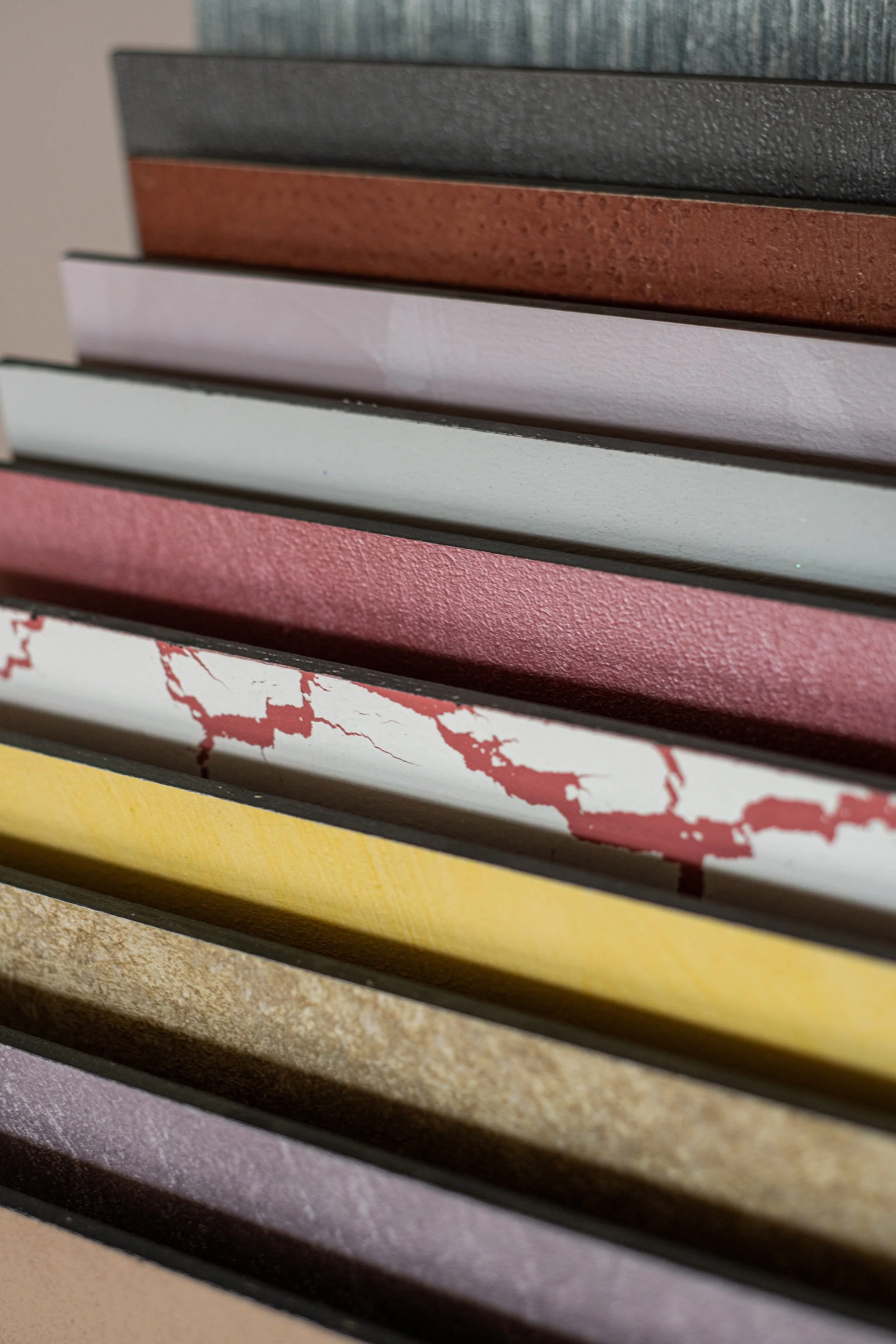 Una pila di campioni di materiali diversi con varie texture e colori, disposti in modo sovrapposto.