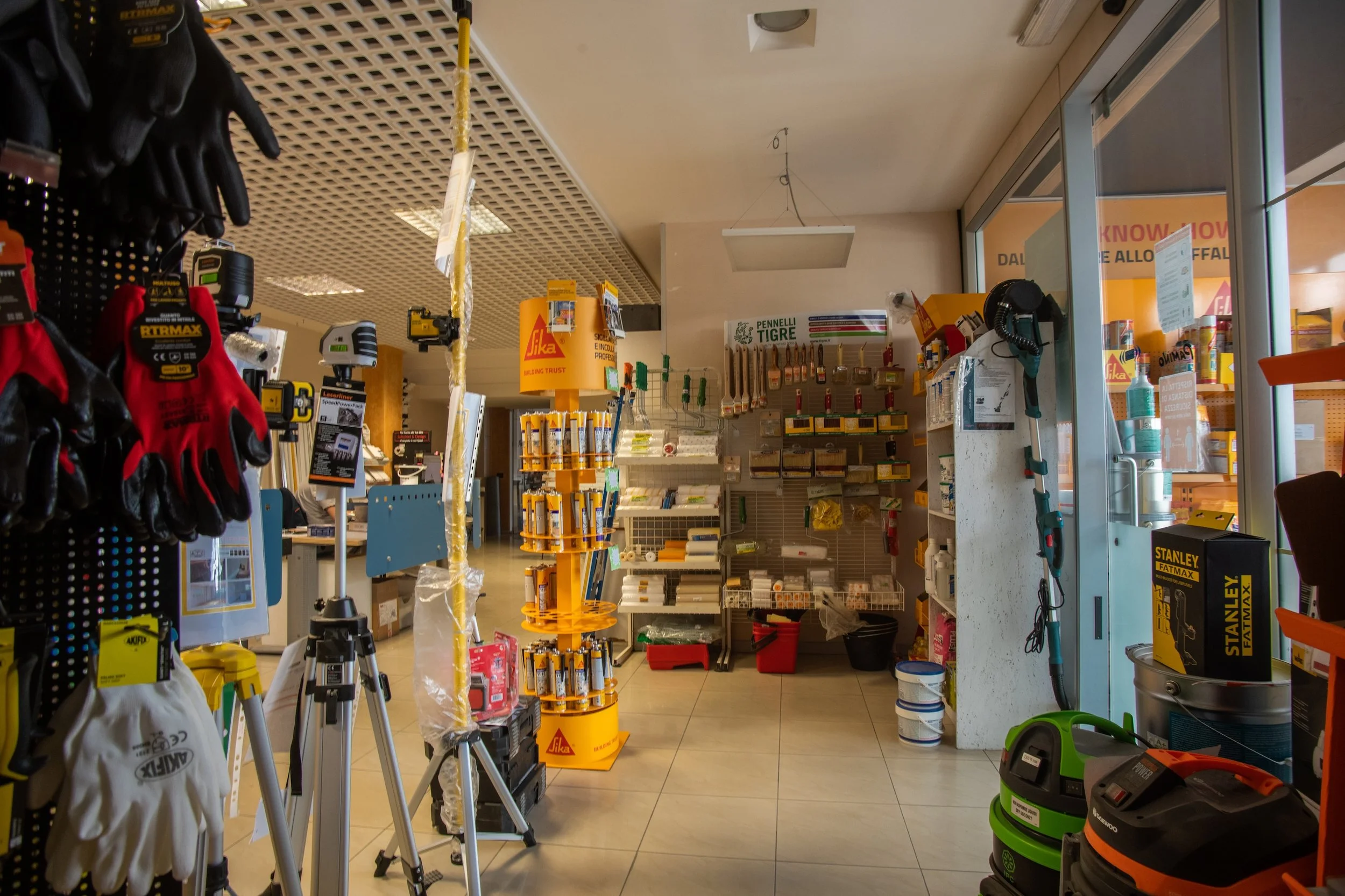 Negozi di ferramenta con attrezzi, guanti, lampade e prodotti vari in esposizione