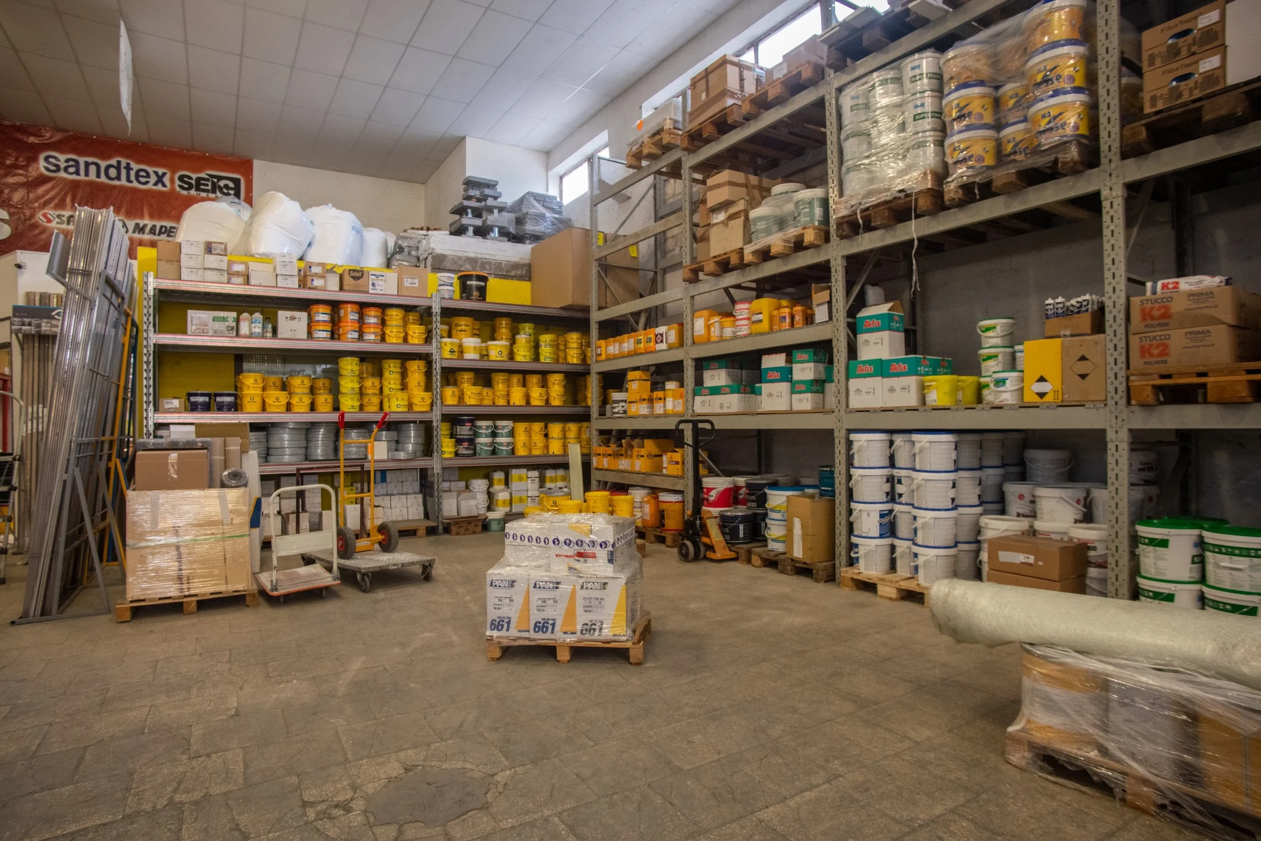 Magazzino con scaffalature cariche di vernici, adesivi e materiali per edilizia
