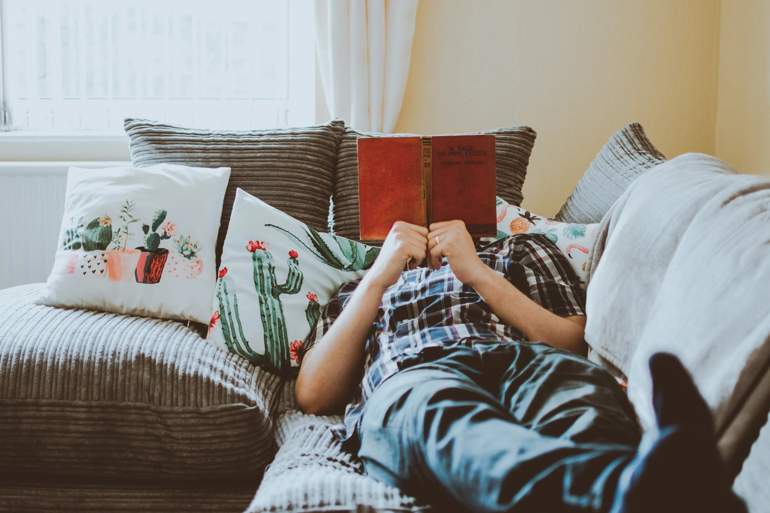 inertia isn't laziness. person resting on couch with an open book over their face