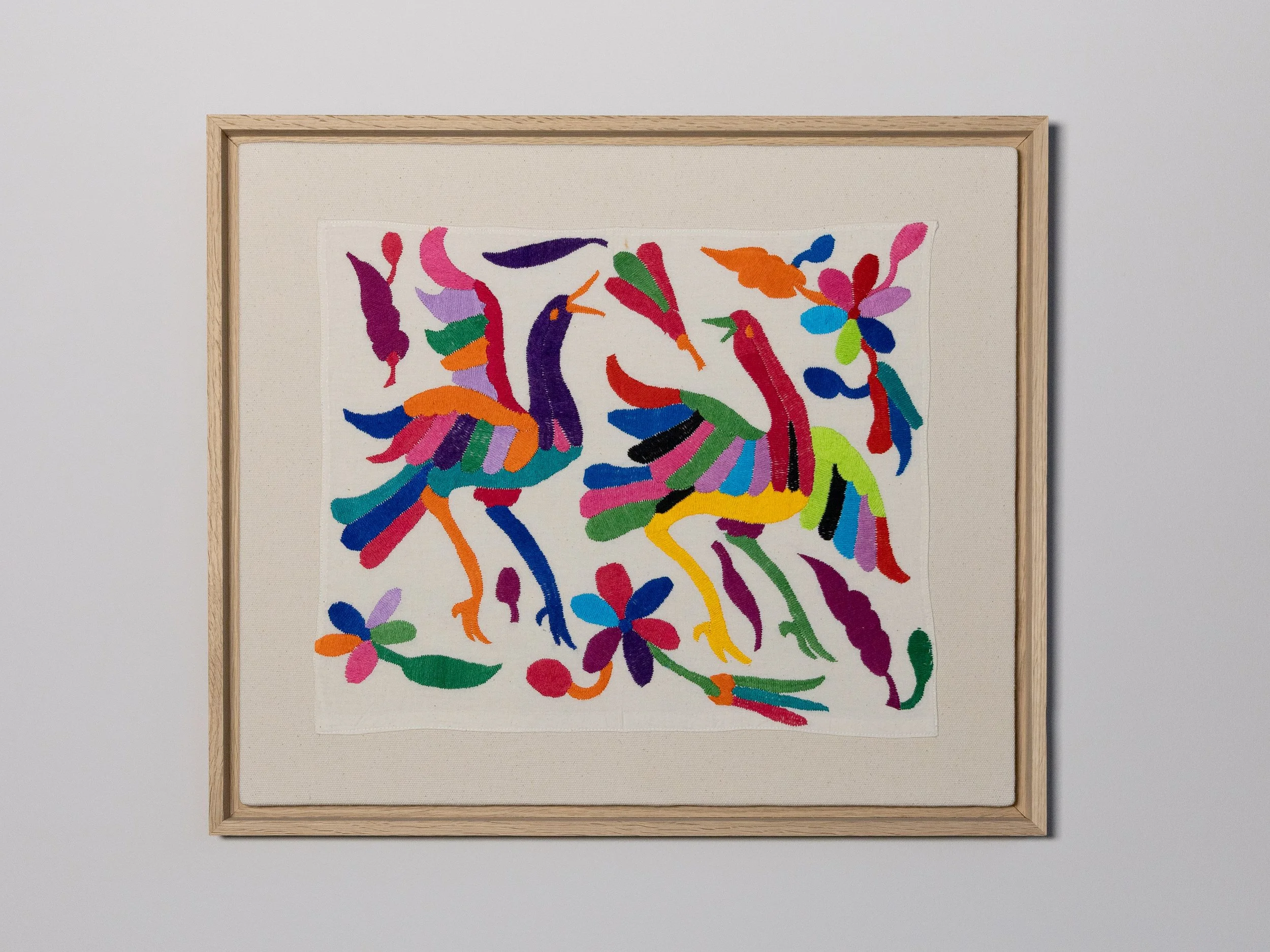 Farbiges gesticktes Bild mit zwei stilisierten Vögeln und Blumen, gerahmt