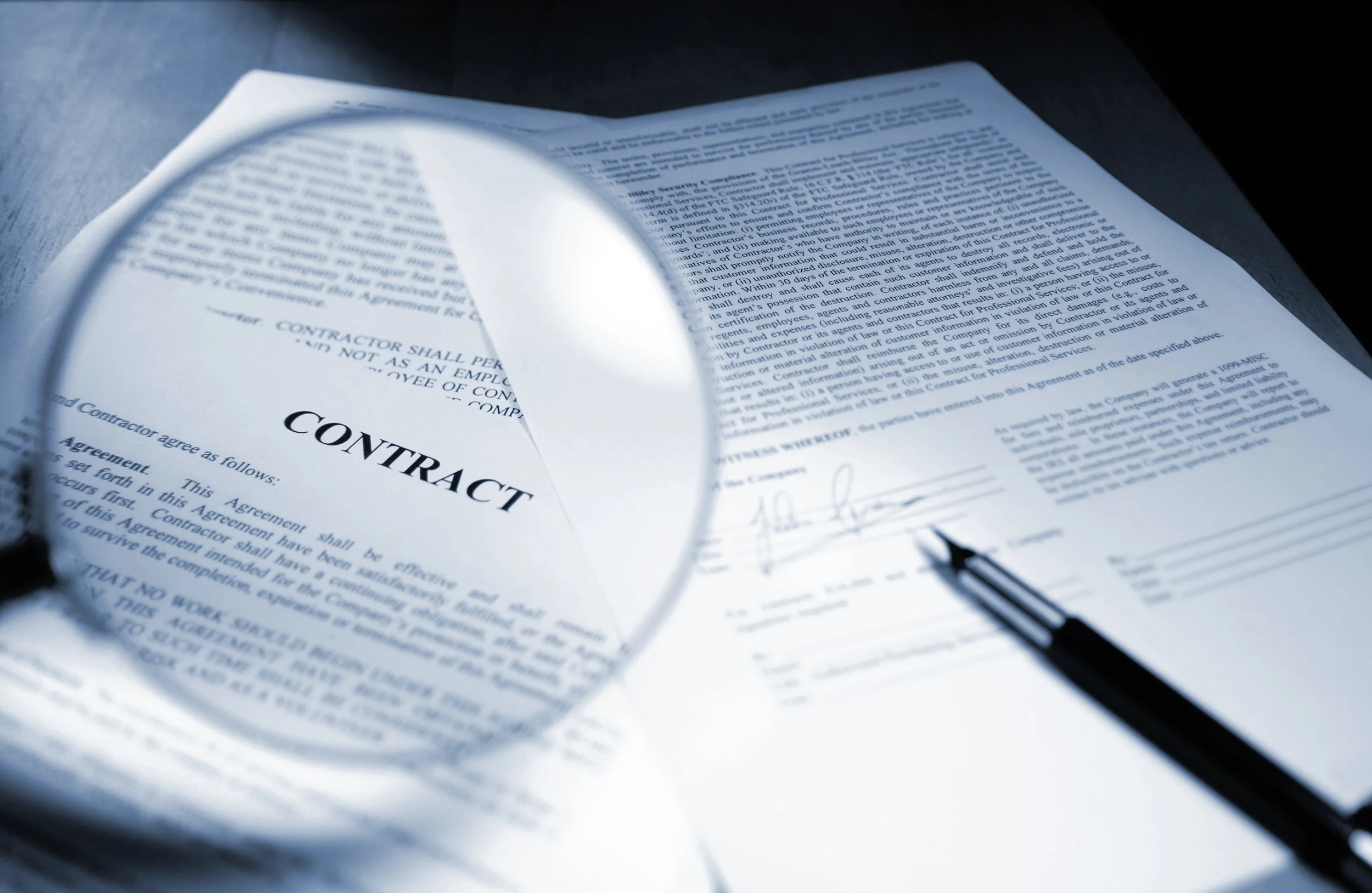 magnifying glass enlarging the word contract in front of printed documents and signature line for factoring contract