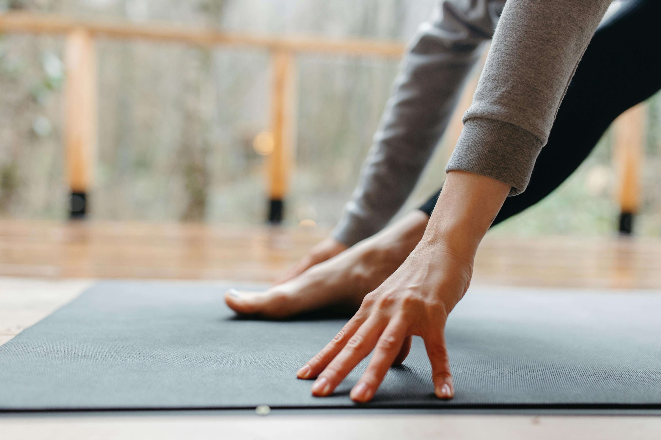 Person practicing yoga or stretching on a mat in an outdoor wooden decked area at move well studio wetherby